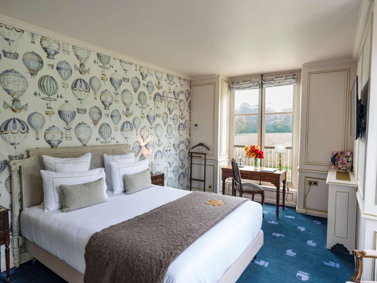 - une chambre avec un grand lit et un mur d'assiettes dans l'établissement Chateau d'Audrieu, à Audrieu