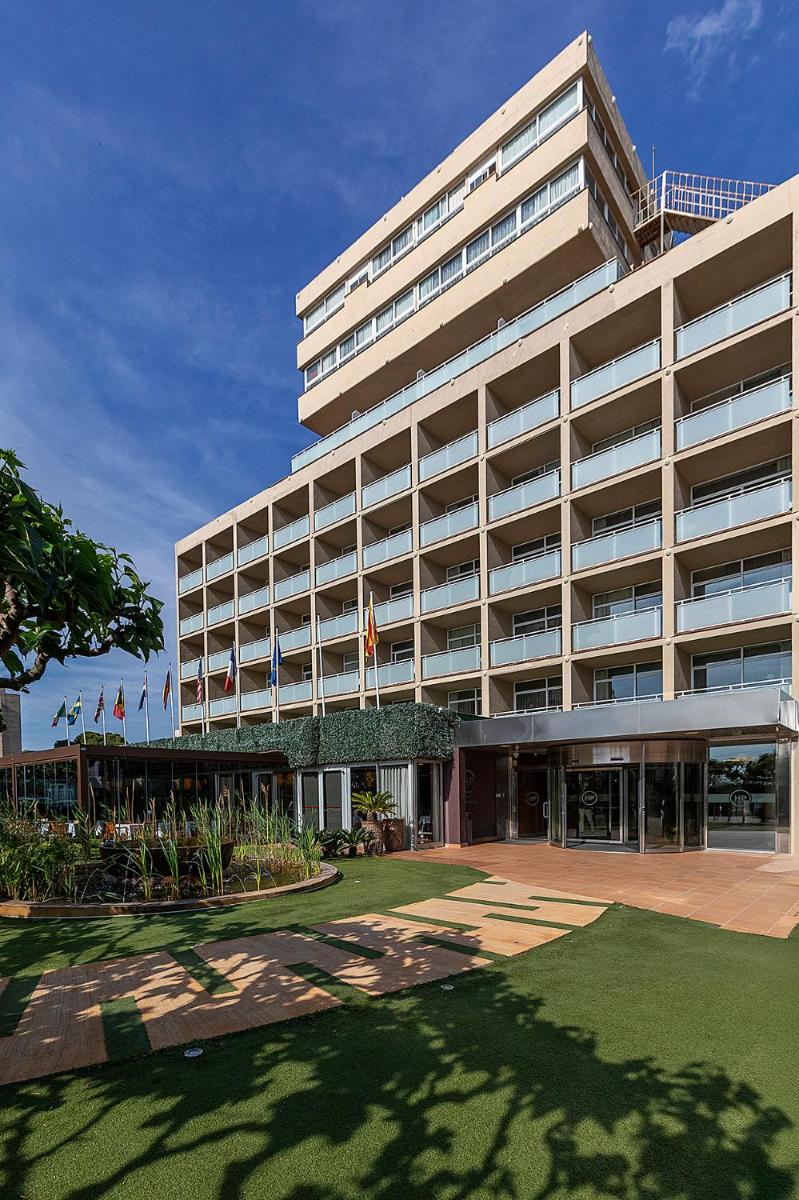 Un gran edificio con césped delante. en Hotel Panorama, en L'Estartit