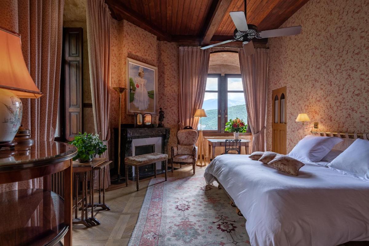 une chambre avec un grand lit et une cheminée dans l'établissement Château De Riell, à Molitg-les-Bains