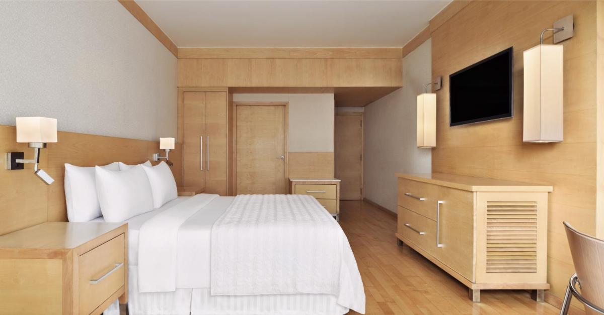 a bedroom with a large white bed and a tv at Le Meridien New Delhi in New Delhi a bedroom with a large white bed and a tv at Le Meridien New Delhi in New Delhi