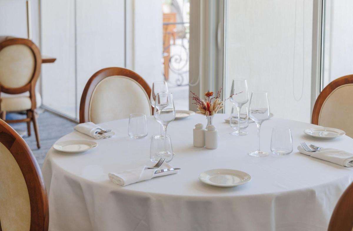 - une table blanche avec des verres à vin et des serviettes dans l'établissement Hotel Corsica & Spa Serena, à Calvi - une table blanche avec des verres à vin et des serviettes dans l'établissement Hotel Corsica & Spa Serena, à Calvi