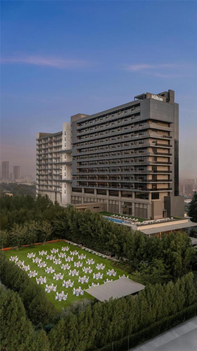 a large building with a field of flowers in front of it at Hilton Gurugram Baani City Centre in Gurgaon