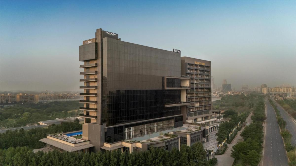 a tall building with a pool in front of it at Hilton Gurugram Baani City Centre in Gurgaon