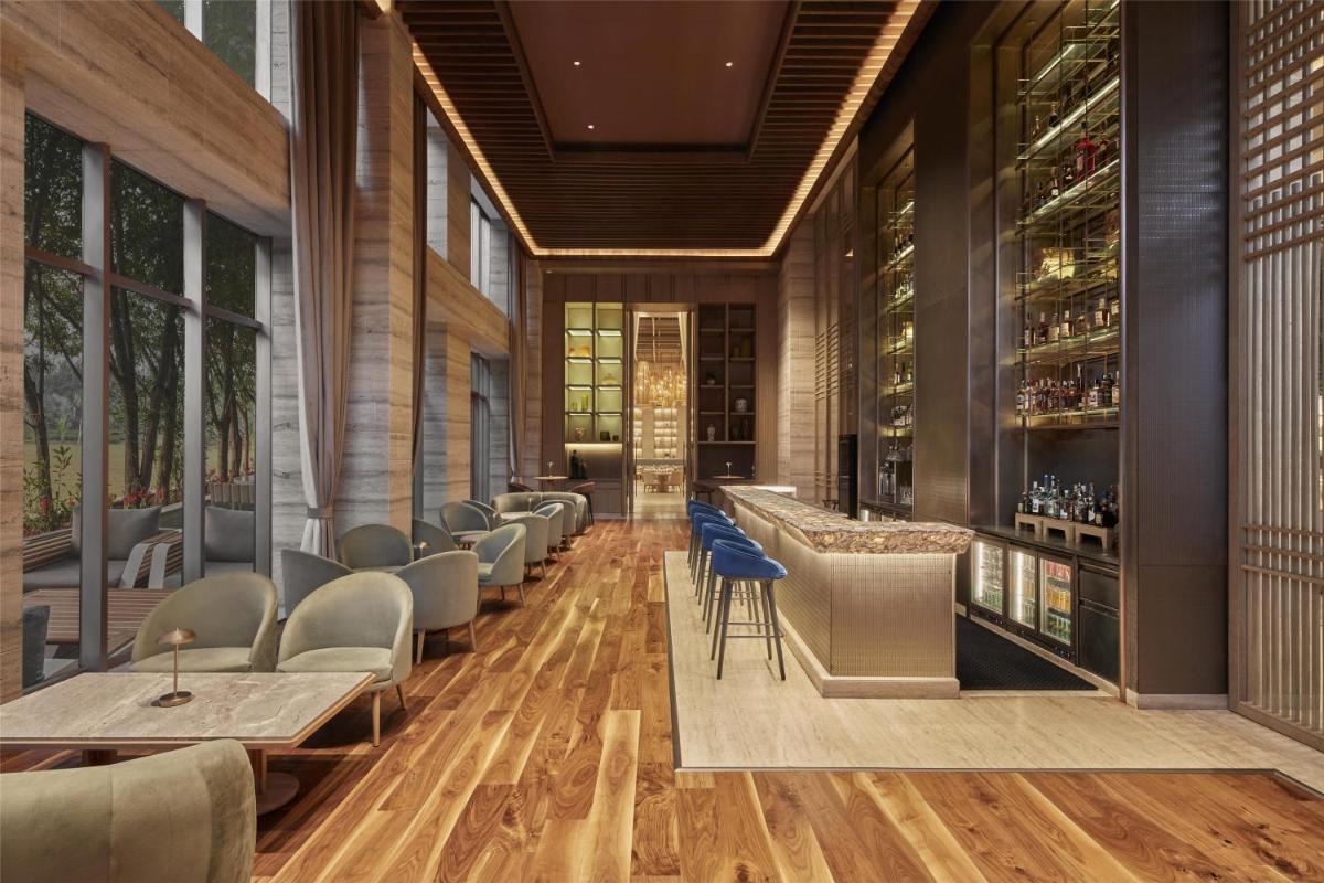 a restaurant with a bar with chairs and tables at Hilton Gurugram Baani City Centre in Gurgaon