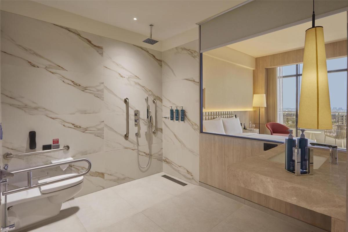 a bathroom with a shower and a toilet and a mirror at Hilton Gurugram Baani City Centre in Gurgaon
