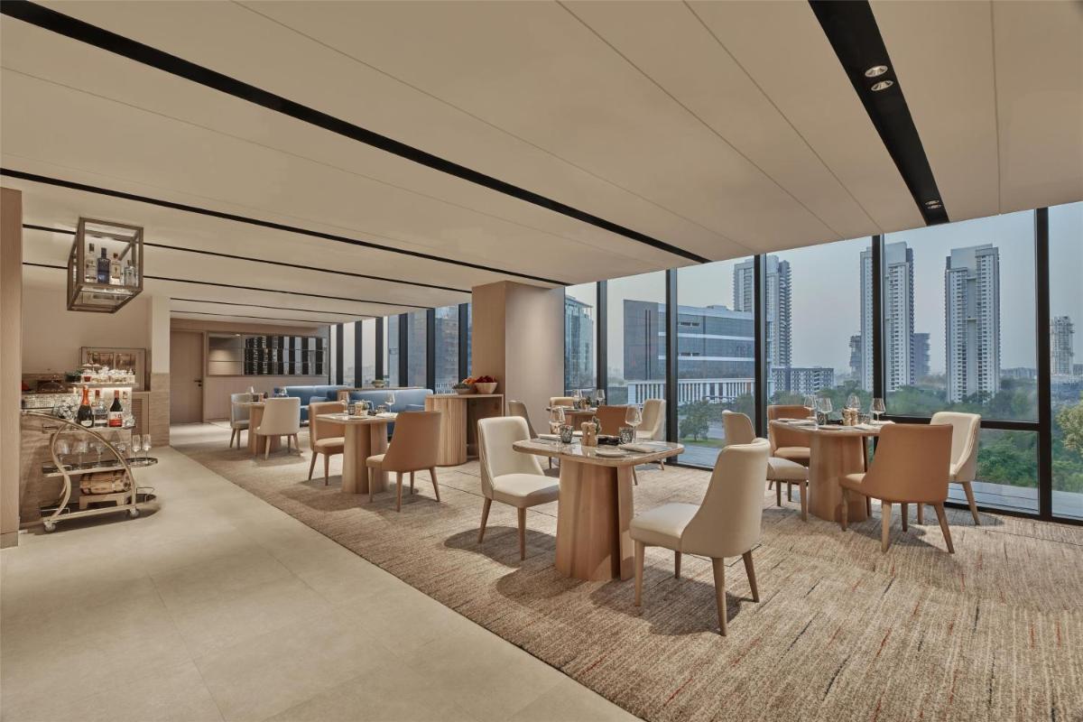 a restaurant with tables and chairs and large windows at Hilton Gurugram Baani City Centre in Gurgaon