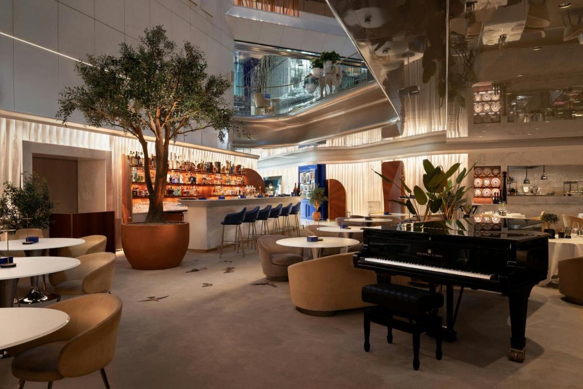 un restaurant avec un piano, des tables et un bar dans l'établissement JW Marriott Cannes, à Cannes