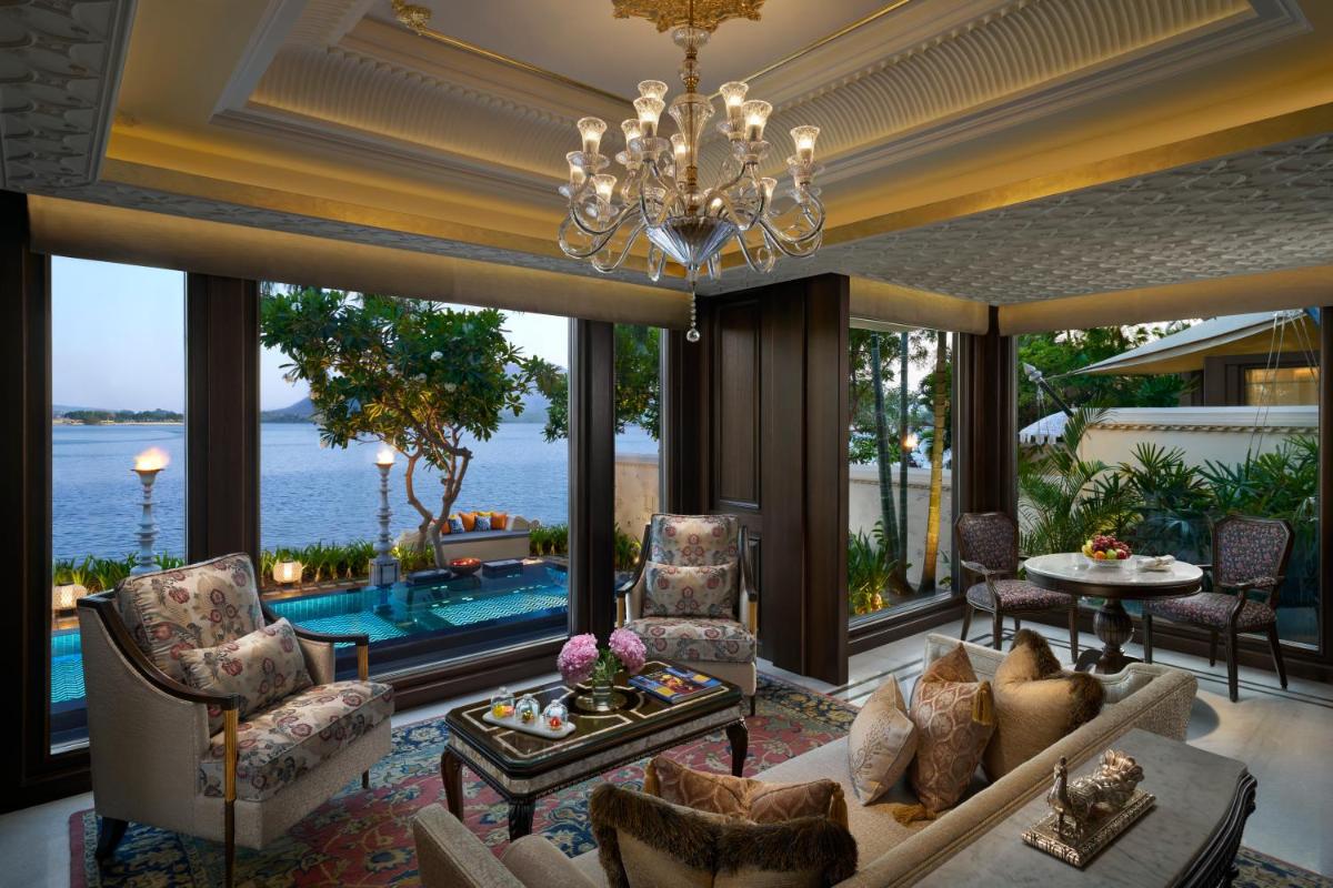 a living room with a chandelier and large windows at The Leela Palace Udaipur in Udaipur