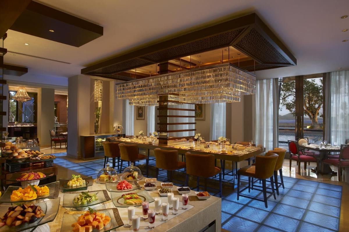 a dining room with a table filled with food at The Leela Palace Udaipur in Udaipur