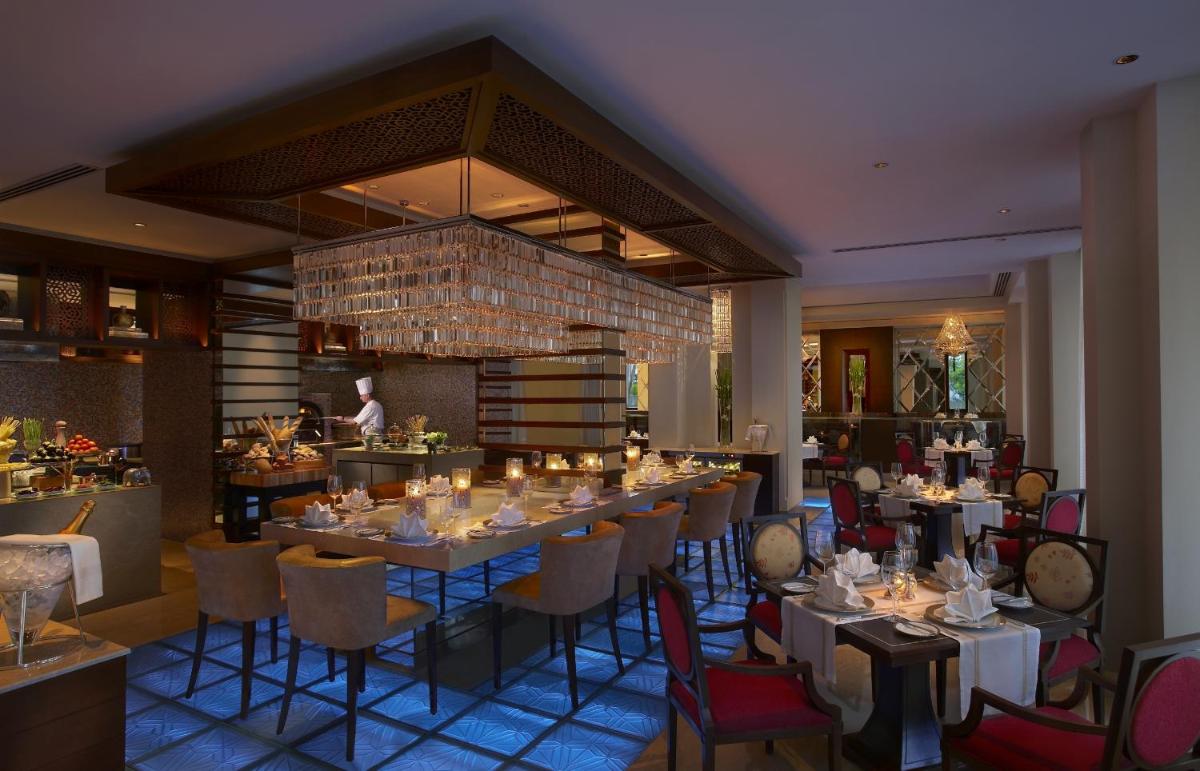 a dining room with a long table and chairs at The Leela Palace Udaipur in Udaipur a dining room with a long table and chairs at The Leela Palace Udaipur in Udaipur