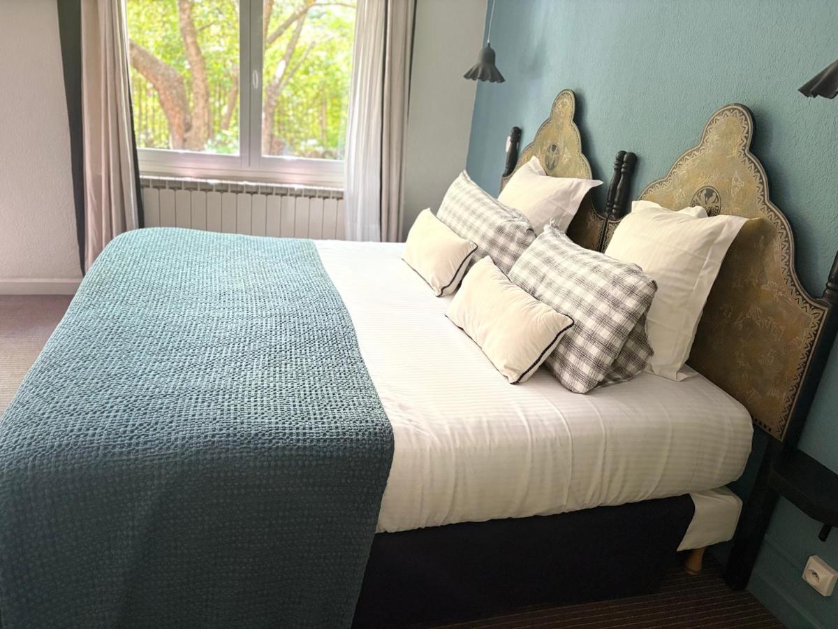 une chambre avec un lit avec des oreillers dessus dans l'établissement Hotel Spa Azteca Barcelonnette, à Barcelonnette