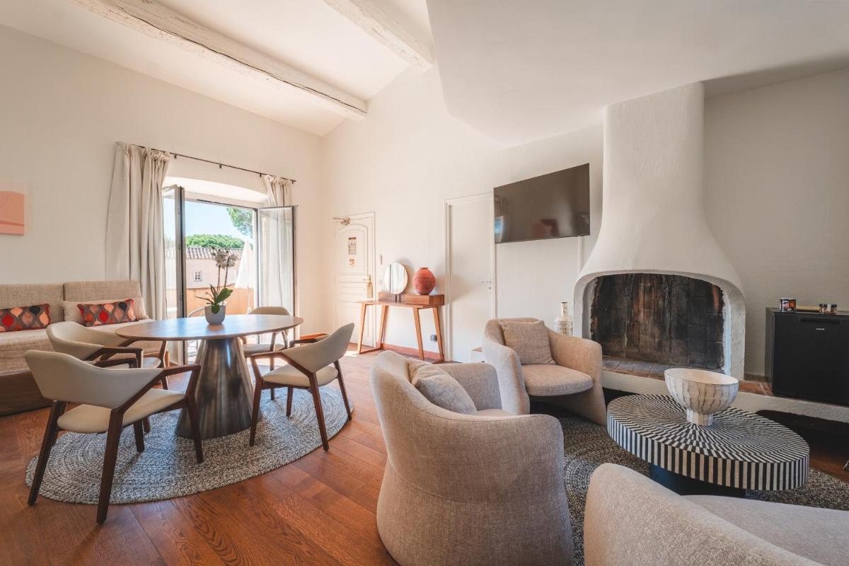 un salon avec une table et des chaises et une cheminée dans l'établissement Hôtel La Mandarine, à Saint-Tropez