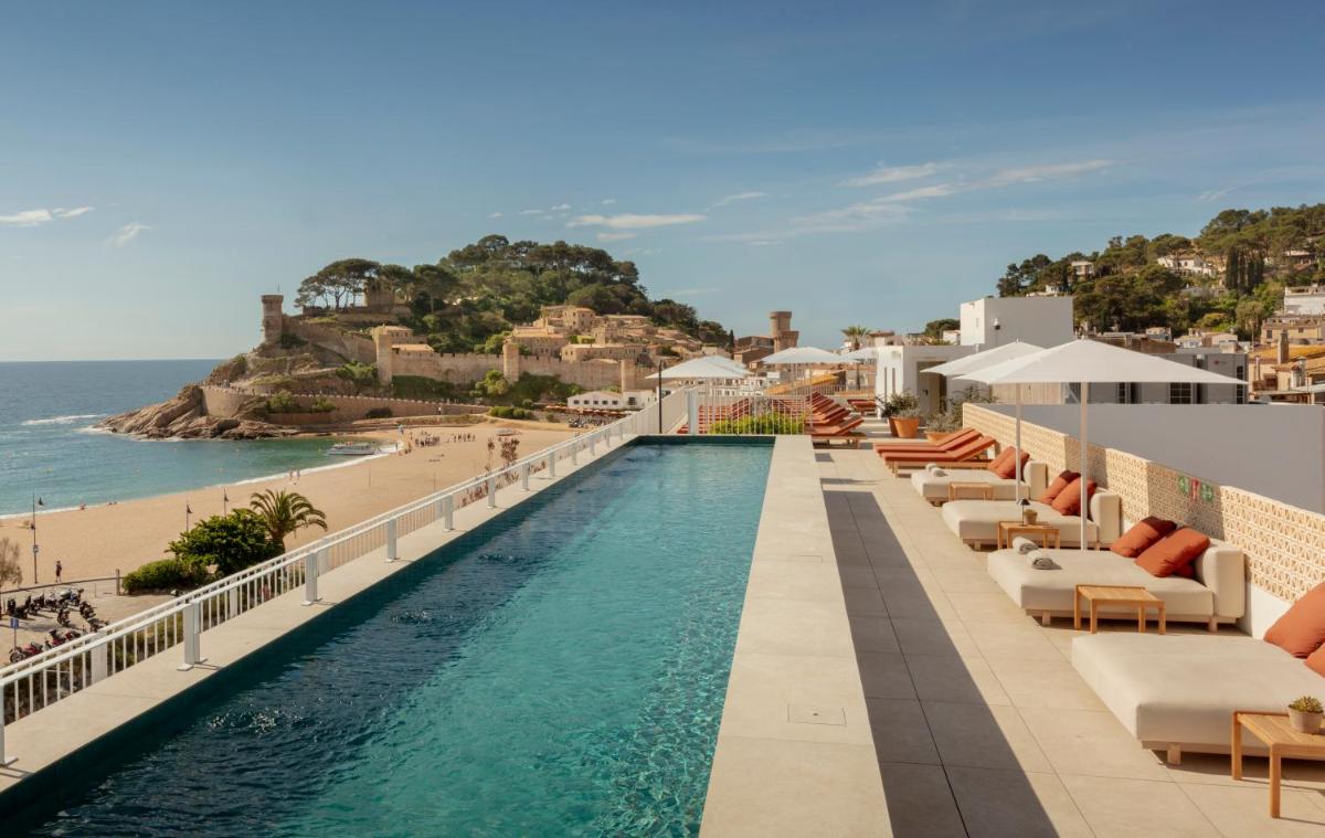una piscina con tumbonas y una playa en Elisabeth by the Sea Hotel, en Tossa de Mar