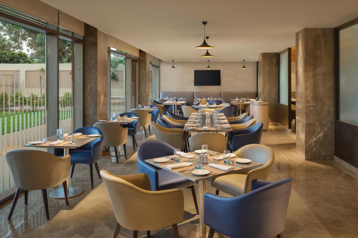 a restaurant with tables and chairs and a screen at Courtyard by Marriott Tiruchirappalli in Tiruchchirāppalli
