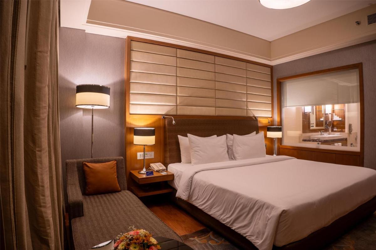a hotel room with a large bed and a chair at Radisson Blu Hotel, Nagpur in Nagpur