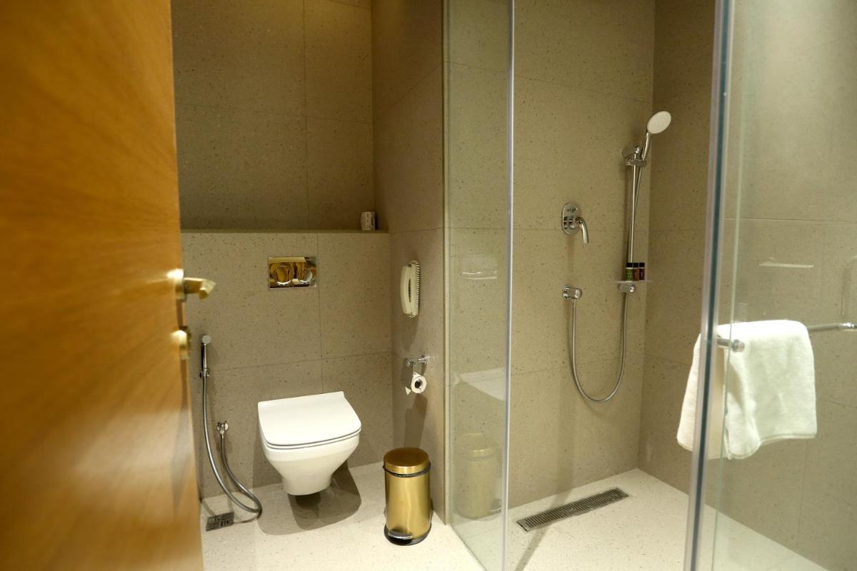 a bathroom with a toilet and a shower with a glass door at The Centrum in Lucknow
