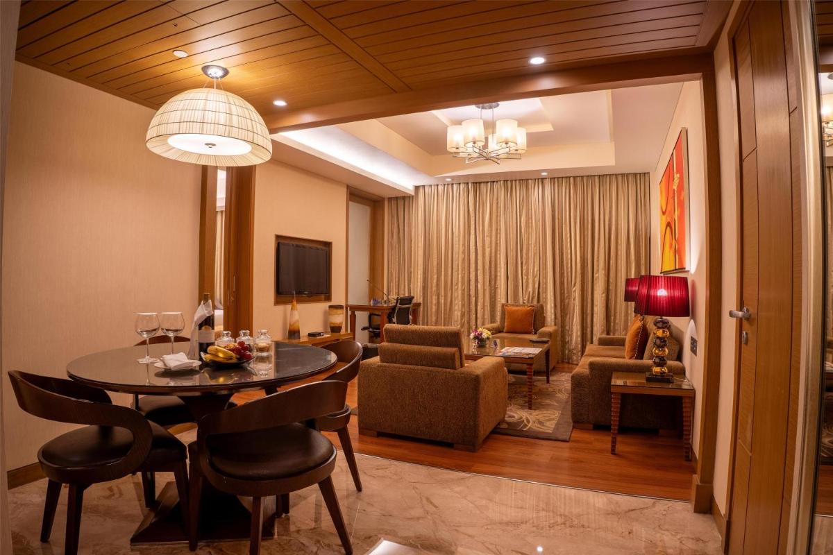 a living room with a table and a dining room at Radisson Blu Hotel, Nagpur in Nagpur