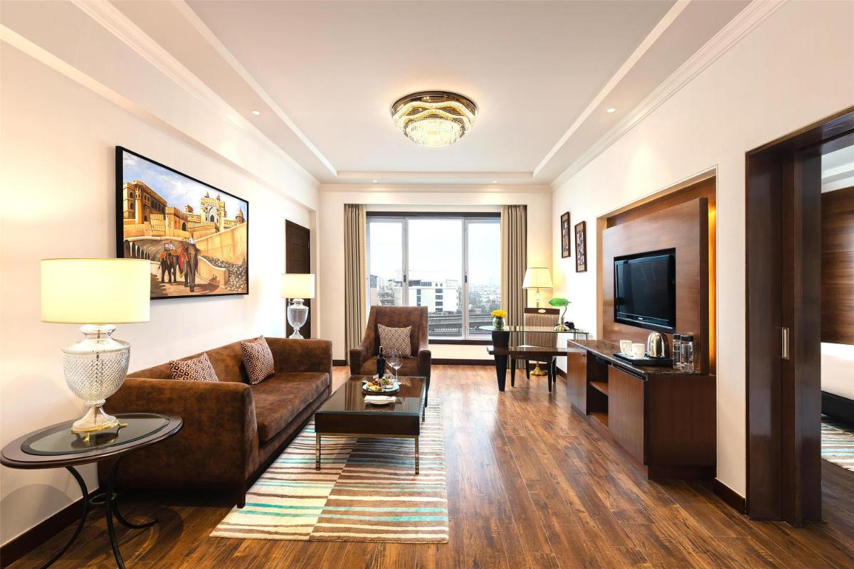 a living room with a couch and a television at Radisson Jaipur City Center in Jaipur