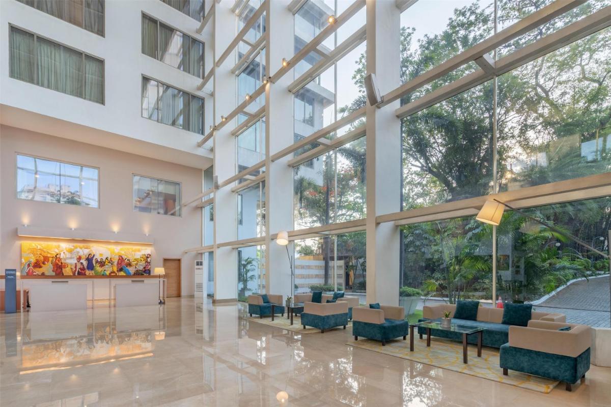 a lobby of a building with tables and chairs at Radisson Blu Plaza Hotel Hyderabad Banjara Hills in Hyderabad a lobby of a building with tables and chairs at Radisson Blu Plaza Hotel Hyderabad Banjara Hills in Hyderabad