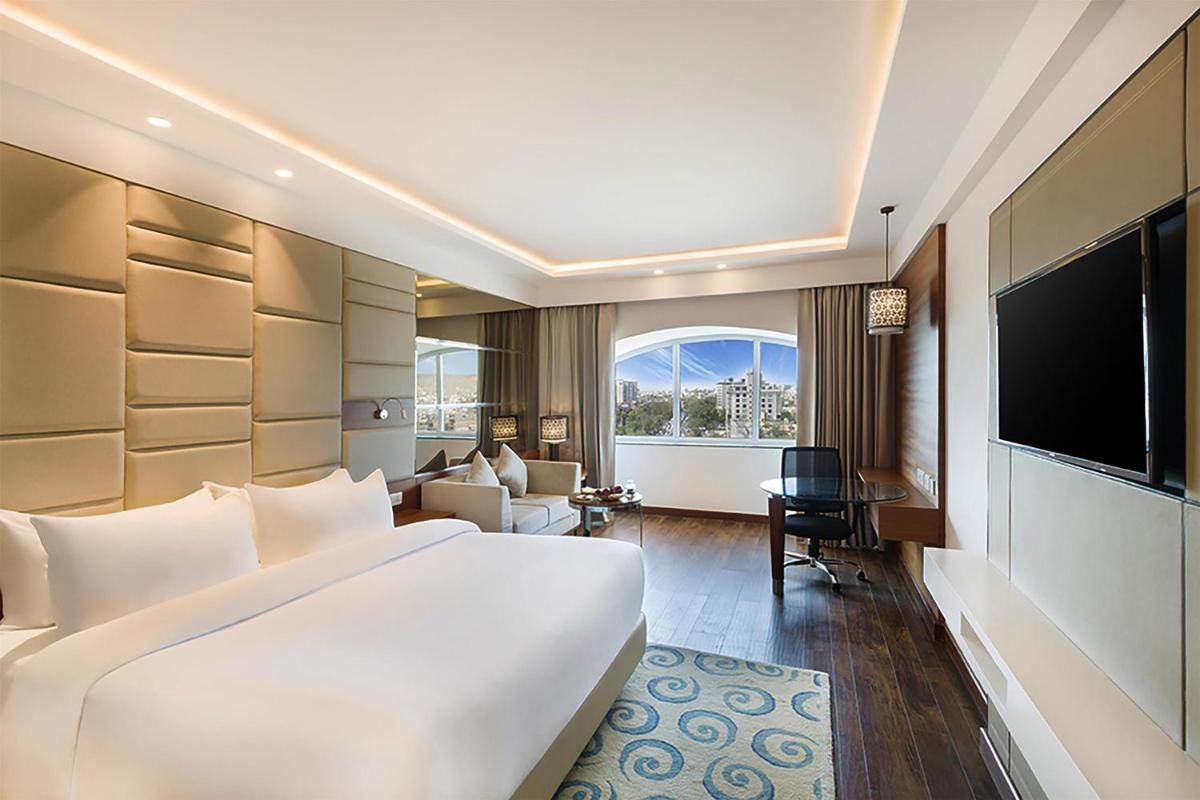 a hotel room with a large bed and a television at Radisson Jaipur City Center in Jaipur