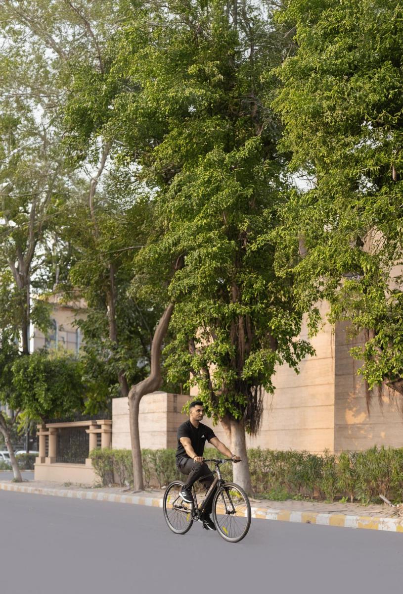a man riding a bike in front of a building at The Leela Ambience Gurugram Hotel & Residences - The Luxury Urban Sanctuary in Gurgaon