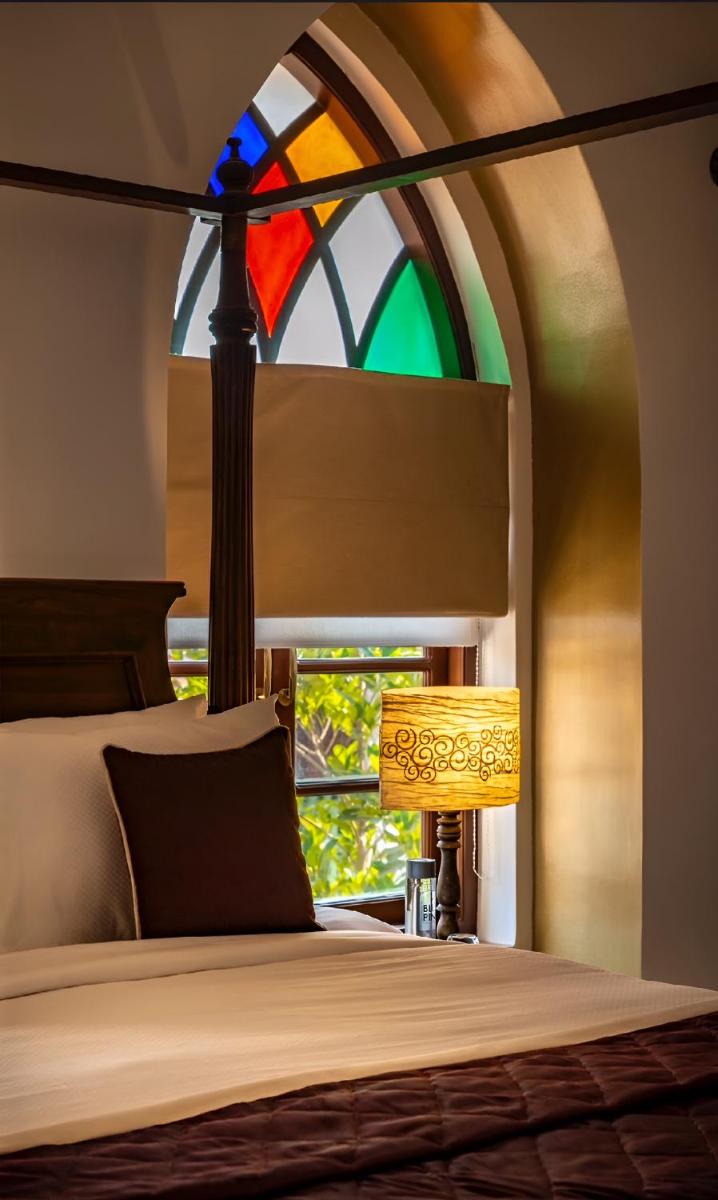 a bedroom with a bed and a stained glass window at The Postcard Cuelim, Goa in Cansaulim