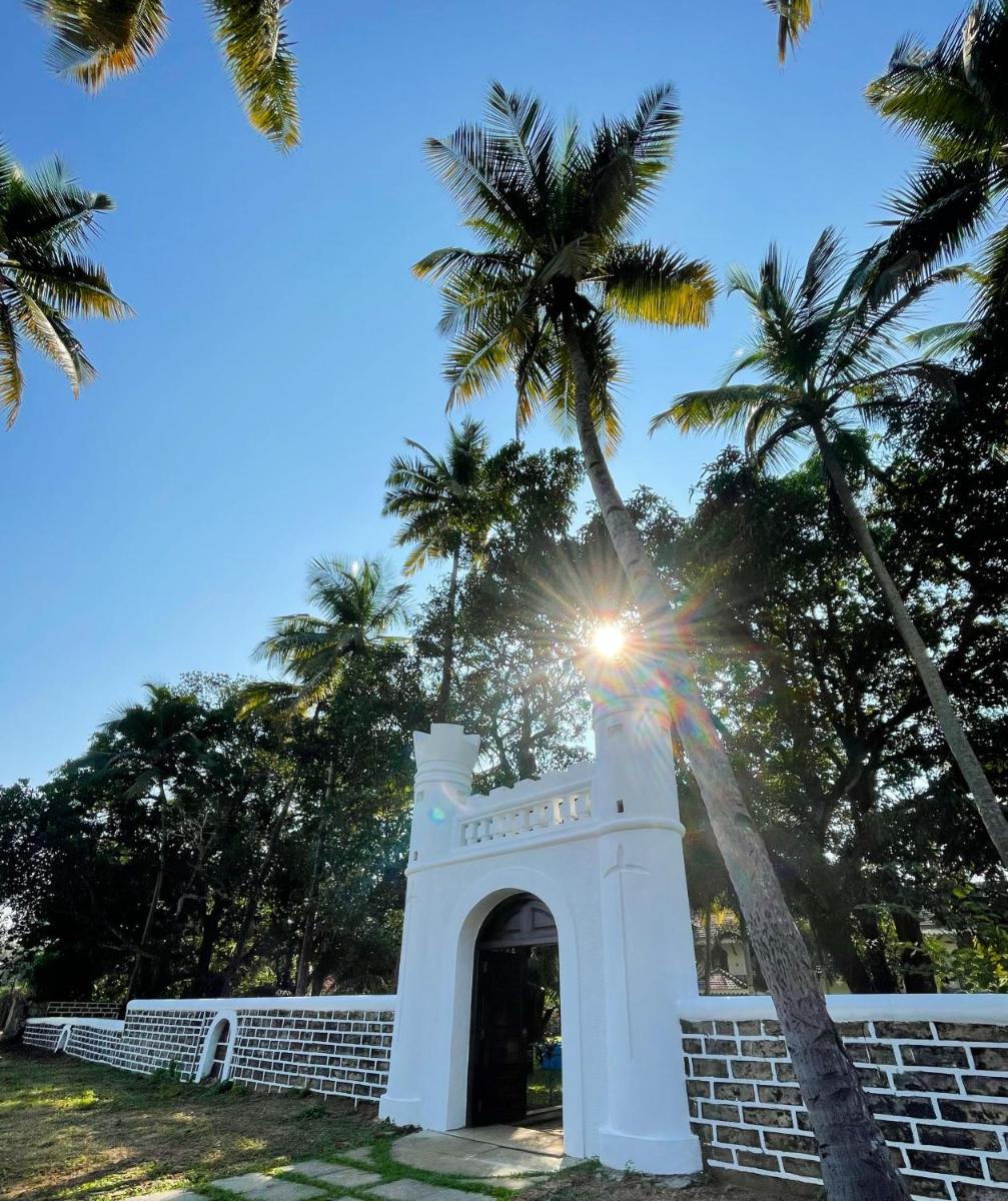 a gate in a wall with palm trees in the background at The Postcard Cuelim, Goa in Cansaulim