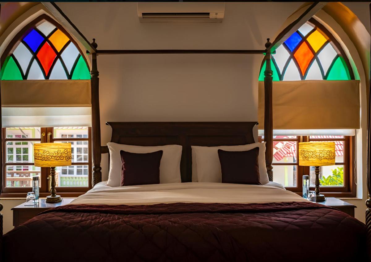 a bedroom with a bed with two stained glass windows at The Postcard Cuelim, Goa in Cansaulim +49 photos