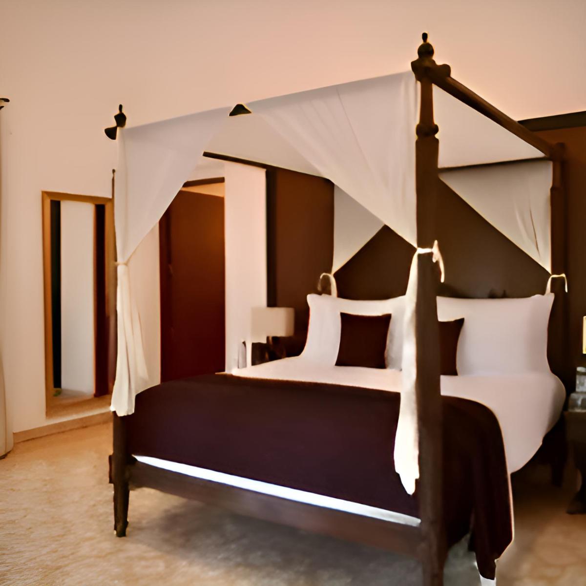 a bedroom with a canopy bed with black and white pillows at The Postcard Cuelim, Goa in Cansaulim