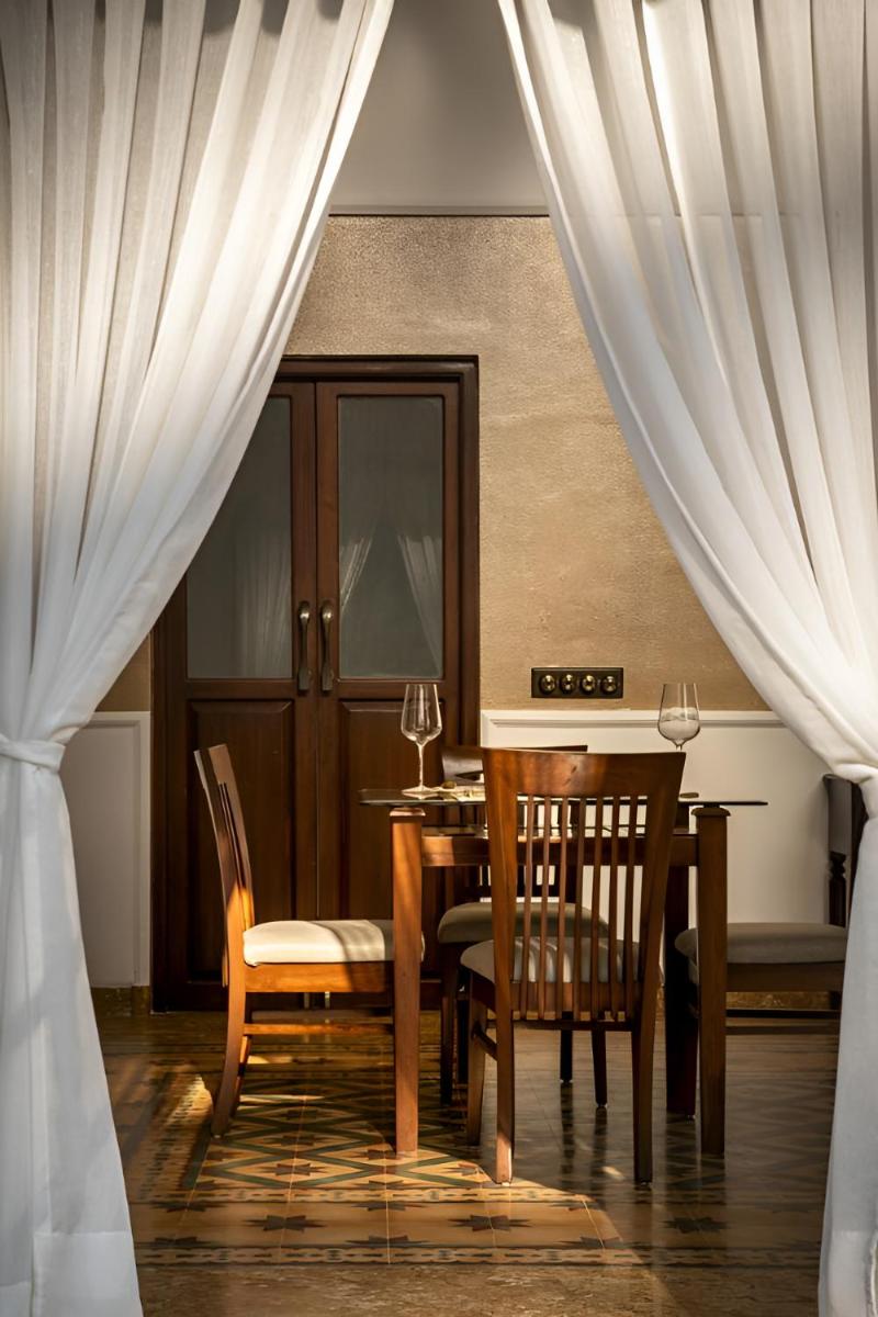 a dining room with a table and chairs and curtains at The Postcard Cuelim, Goa in Cansaulim