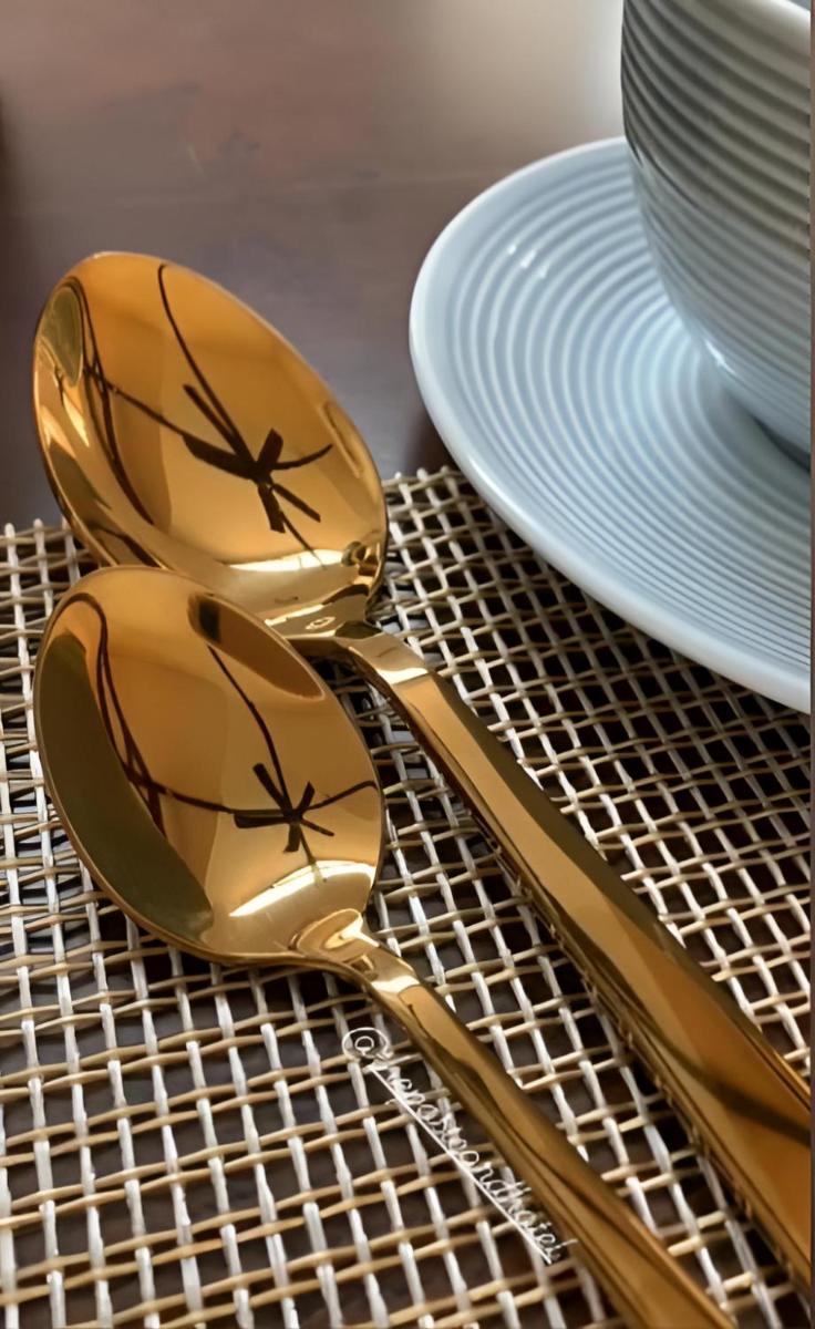 a pair of gold spoons and a plate on a table at The Postcard Cuelim, Goa in Cansaulim