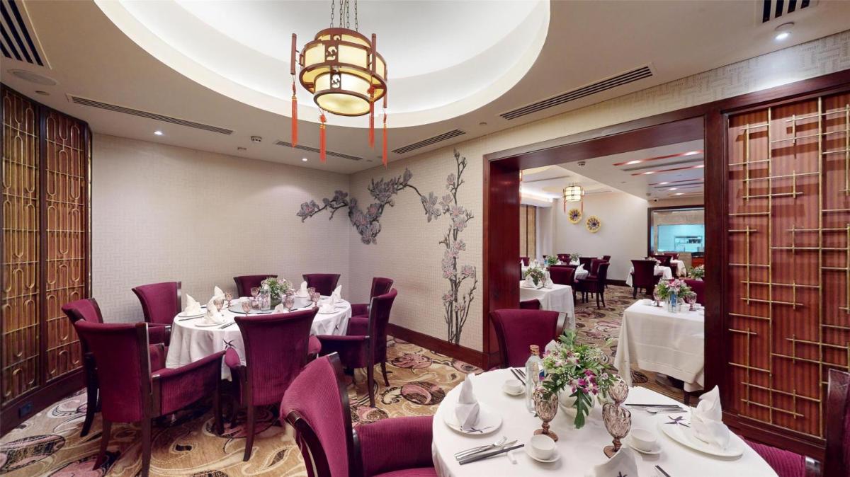 a restaurant with white tables and chairs and a chandelier at Radisson Blu Hotel, Nagpur in Nagpur