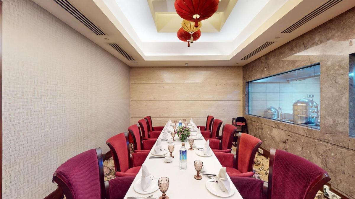 a dining room with a long table and red chairs at Radisson Blu Hotel, Nagpur in Nagpur