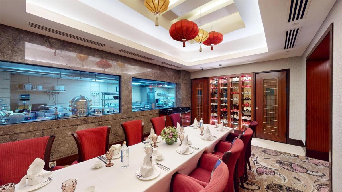 a restaurant with a long table and red chairs at Radisson Blu Hotel, Nagpur in Nagpur