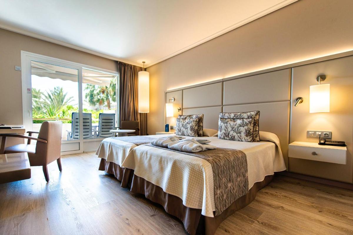 Una habitación de hotel con una cama grande y una mesa. en Spring Arona Gran Hotel - Adults Only, en Los Cristianos