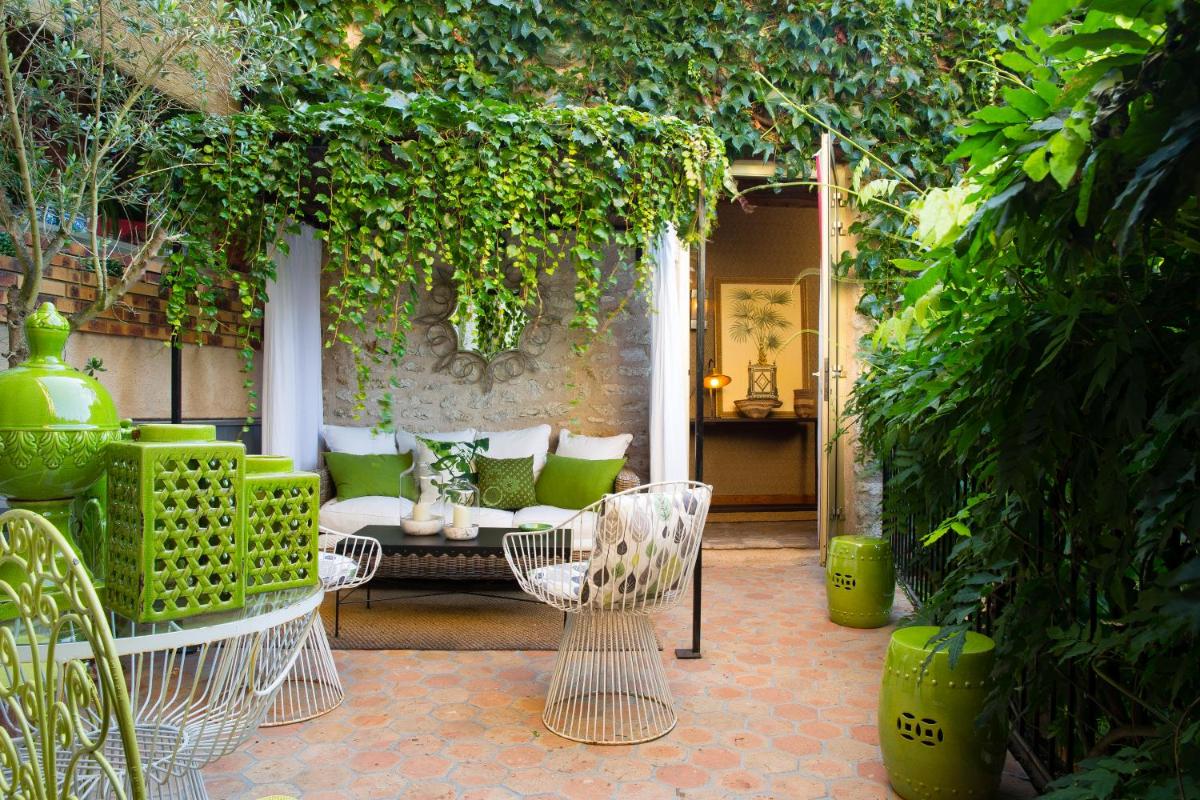 une terrasse avec un canapé, des chaises et des plantes dans l'établissement Hotel De France, à Angerville