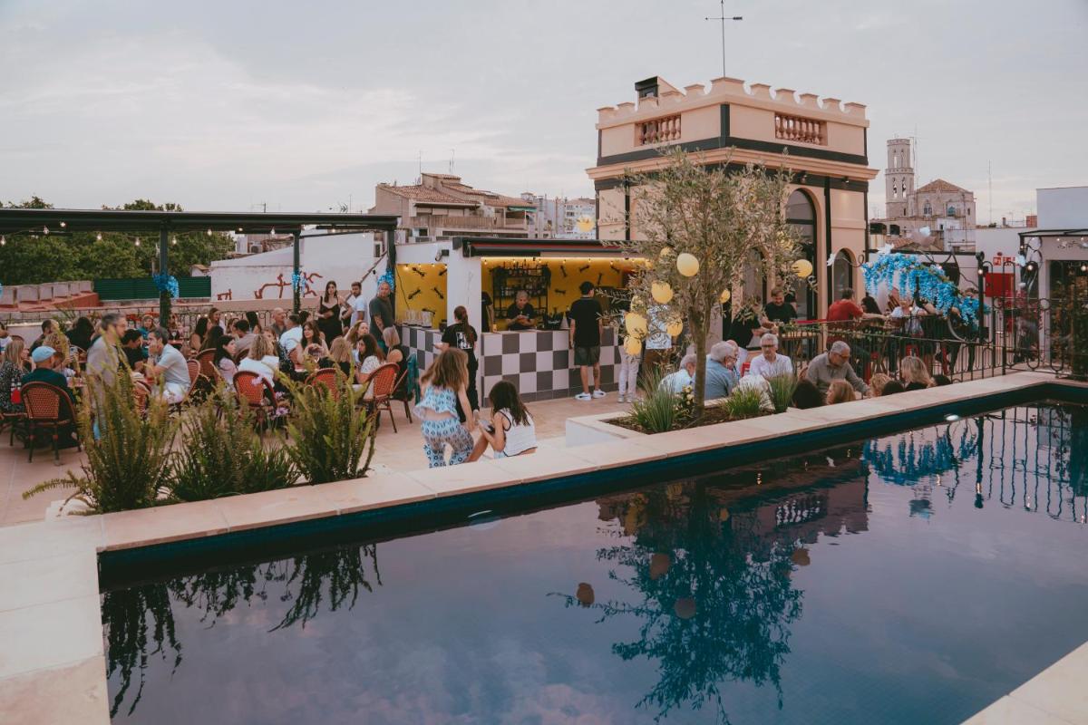 una multitud de personas sentadas alrededor de una piscina en Hotel Divino & Aparthotel, en Figueres una multitud de personas sentadas alrededor de una piscina en Hotel Divino & Aparthotel, en Figueres