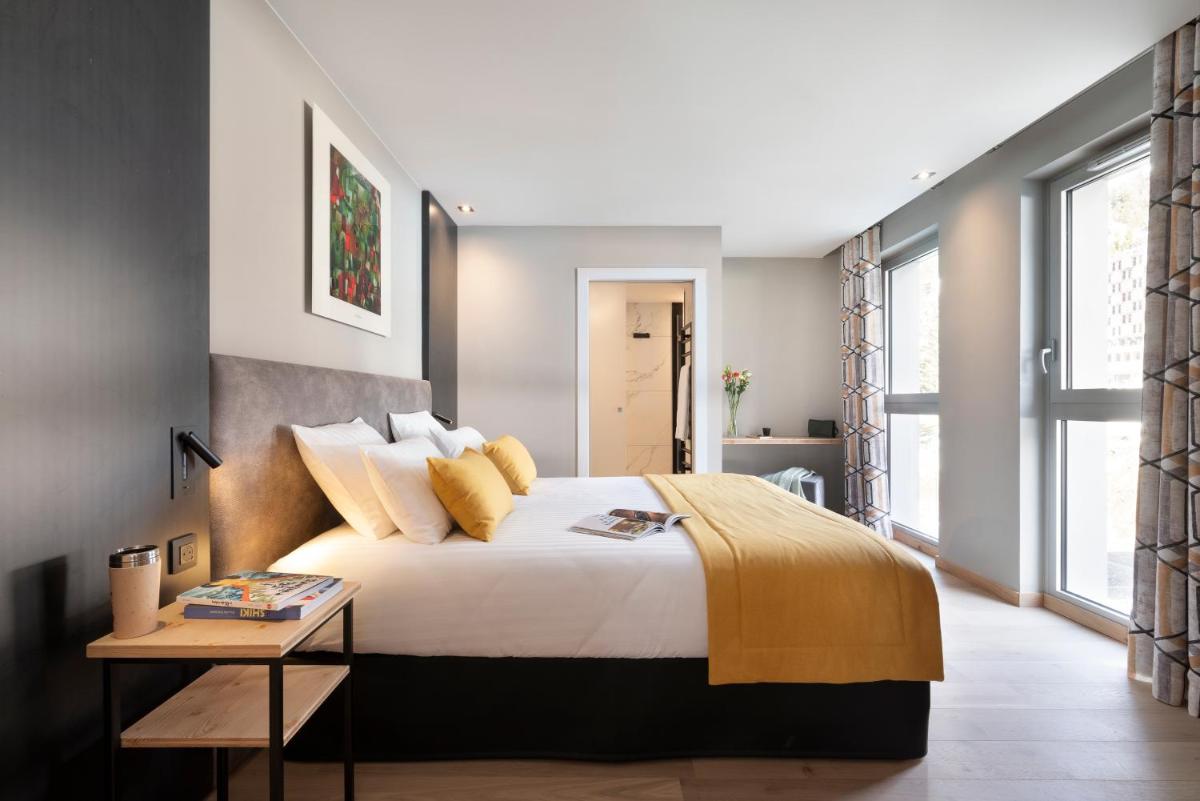 une chambre avec un grand lit et une table dans l'établissement MGM Hôtels & Résidences - Résidence Alhéna, à Flaine 40 autres photos