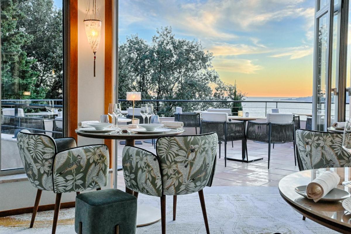 un restaurant avec des tables et des chaises et une vue sur l'eau dans l'établissement Tiara Miramar Beach Resort, à Théoule-sur-Mer