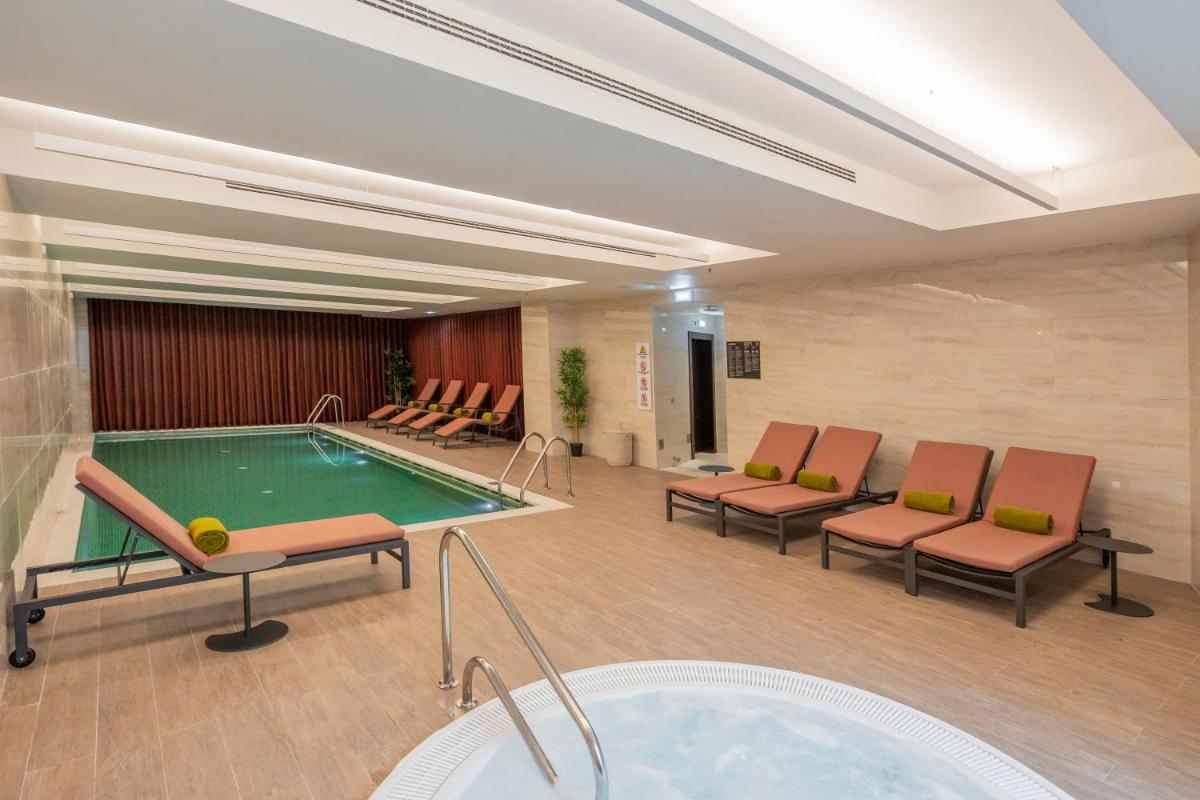 um quarto de hotel com piscina, cadeiras e banheira em Cenica Porto Hotel, Curio Collection By Hilton no Porto
