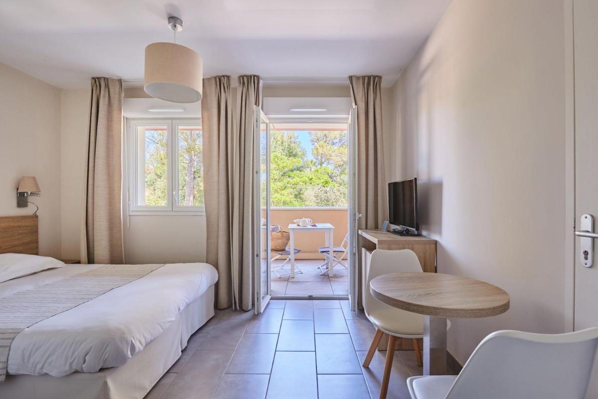une chambre avec un lit, une table et un bureau dans l'établissement Résidence Odalys Les Canissons, à Cavalaire-sur-Mer