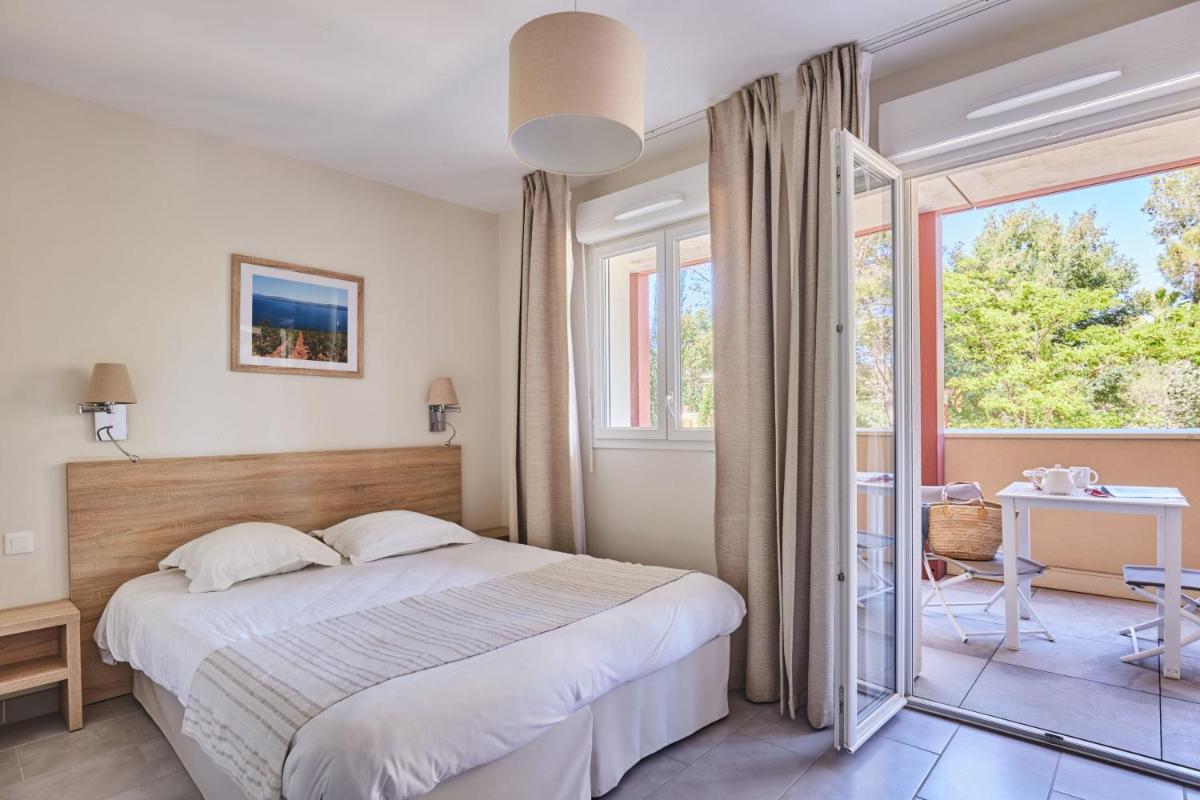 une chambre avec un lit et une grande fenêtre dans l'établissement Résidence Odalys Les Canissons, à Cavalaire-sur-Mer 90 autres photos