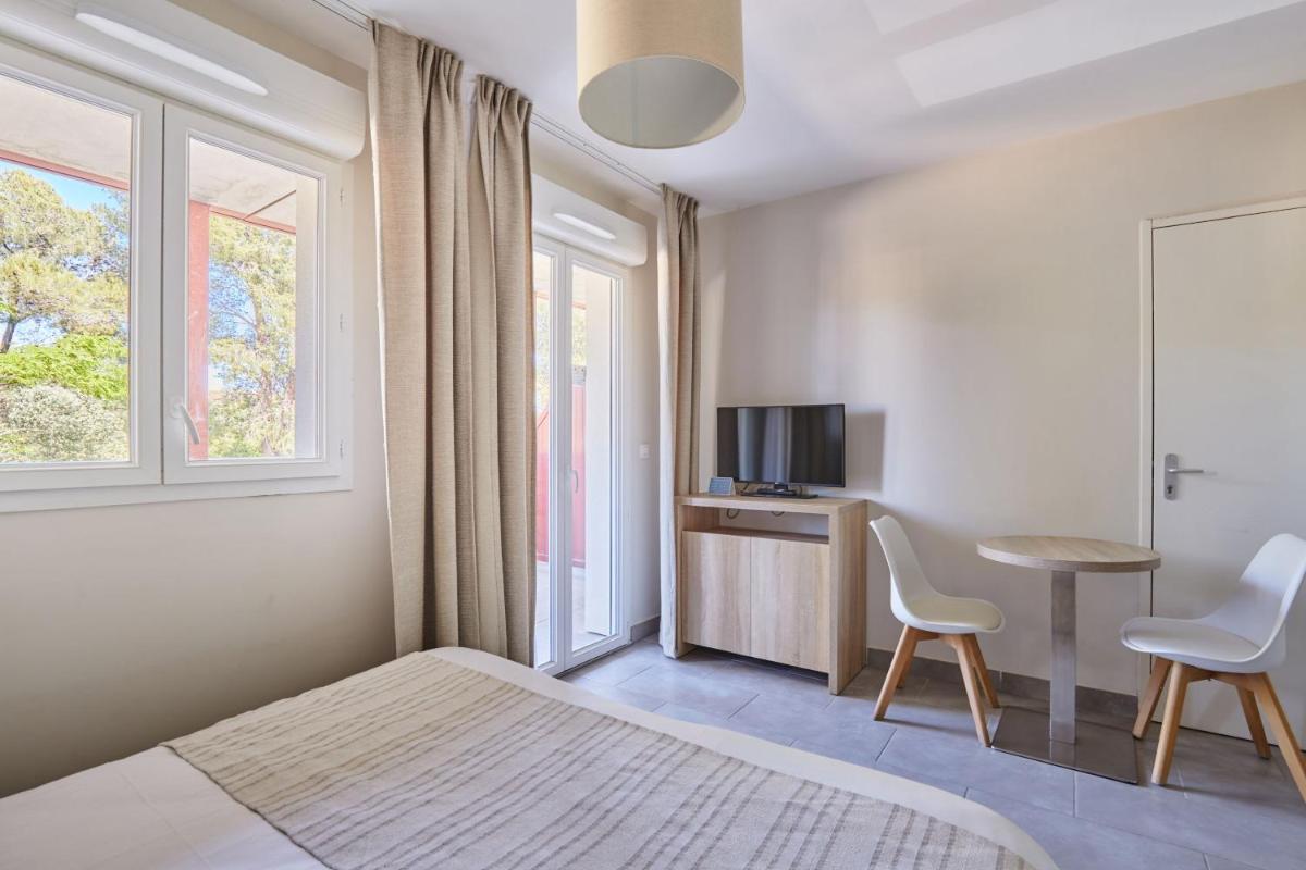 - une chambre avec un lit, une table et deux chaises dans l'établissement Résidence Odalys Les Canissons, à Cavalaire-sur-Mer