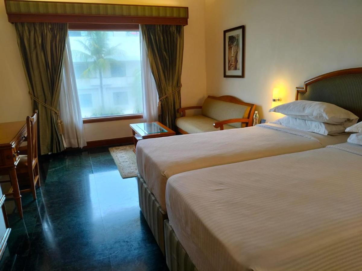 a hotel room with two beds and a window at The Ummed Ahmedabad Airport in Ahmedabad