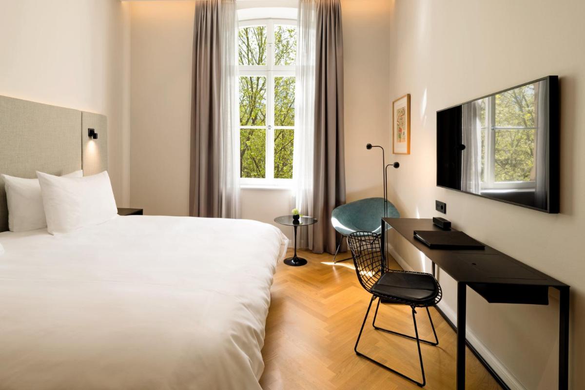 ein Hotelzimmer mit einem Bett, einem Schreibtisch und einem Fenster in der Unterkunft ESPLANADE Saarbrücken in Saarbrücken