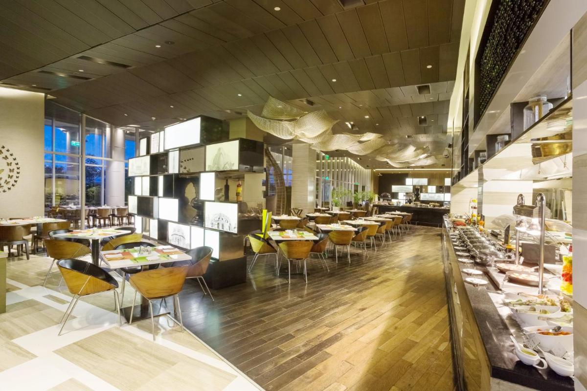 a restaurant with tables and chairs in a room at Holiday Inn New Delhi Aerocity by IHG in New Delhi