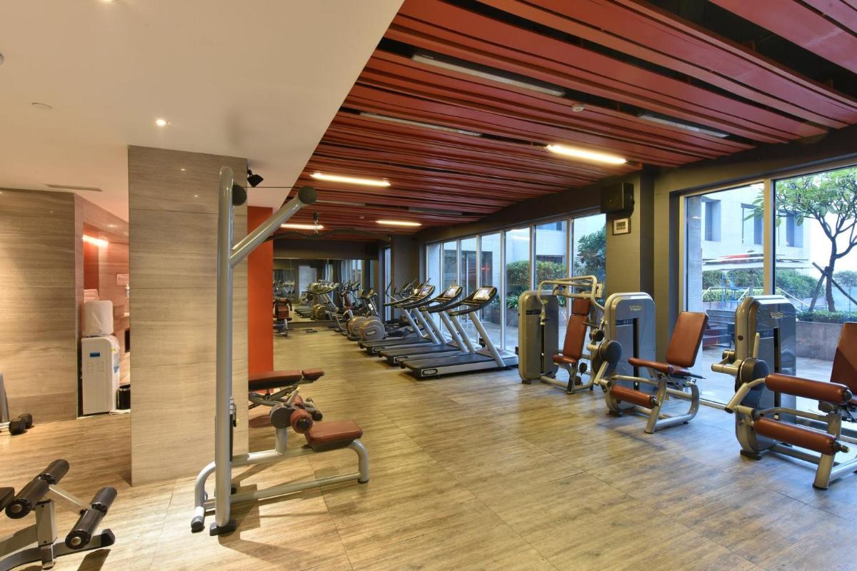 a gym with a row of treadmills and machines at Holiday Inn New Delhi Aerocity by IHG in New Delhi