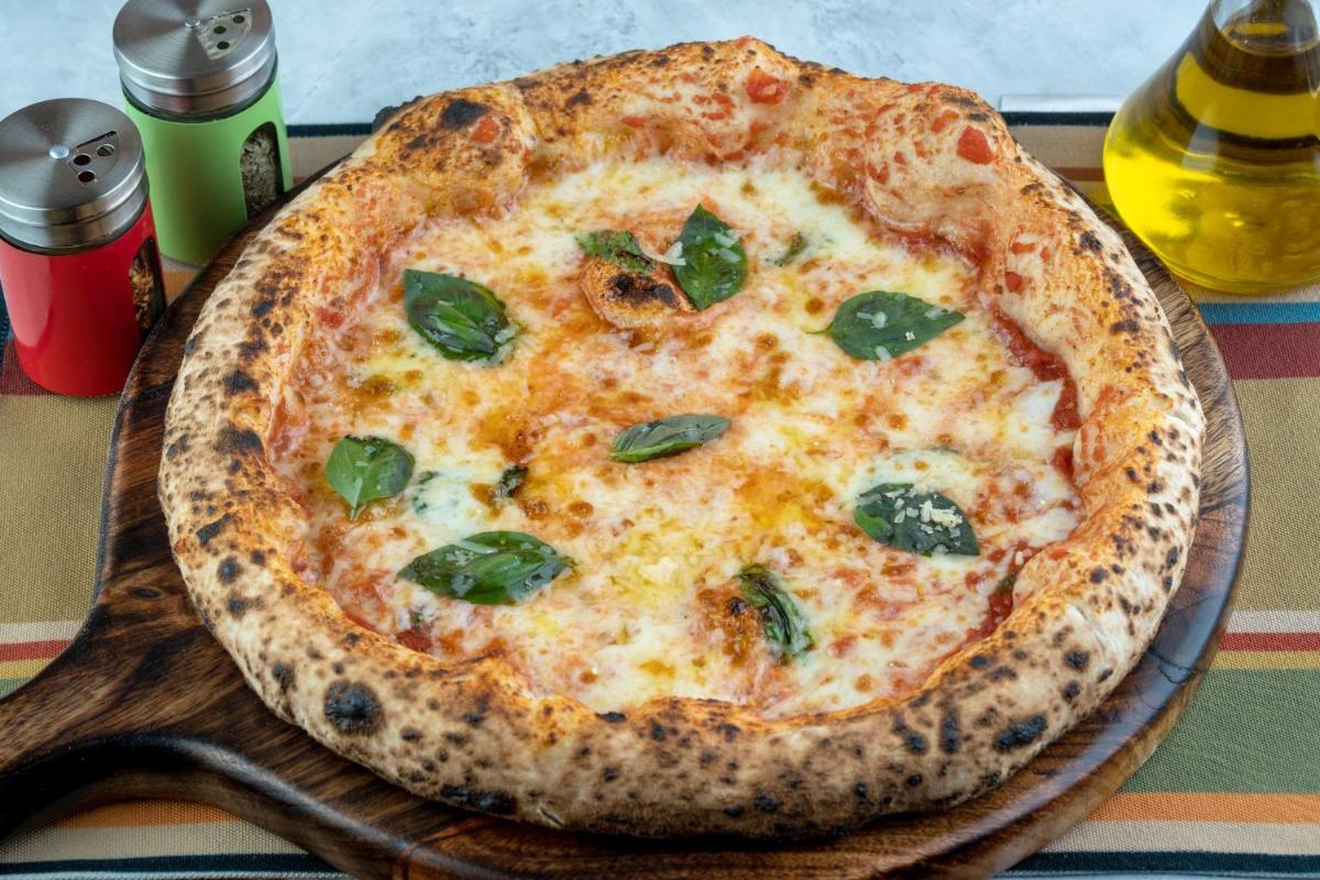 a pizza sitting on a wooden plate on a table at Holiday Inn New Delhi Aerocity by IHG in New Delhi