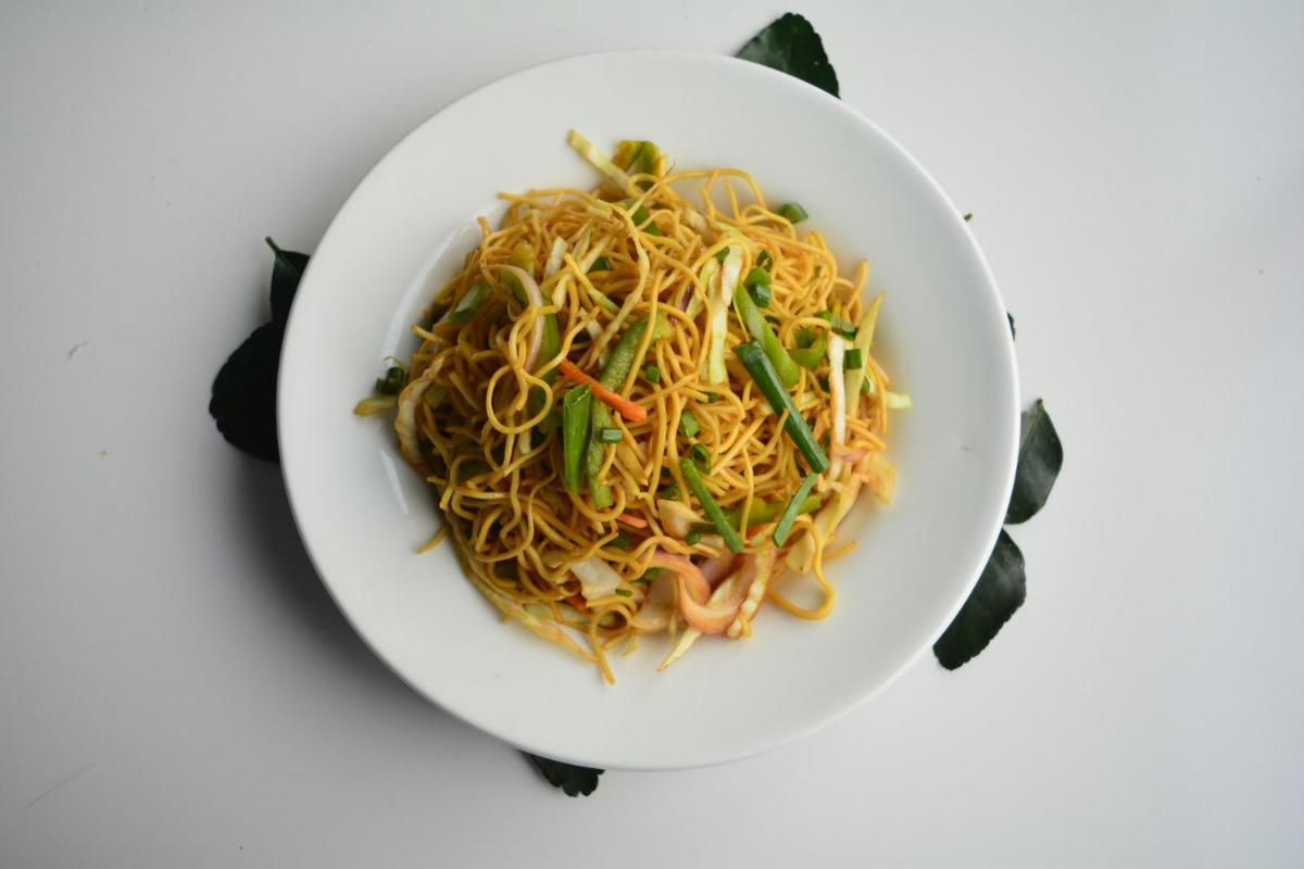 a bowl of noodles with vegetables on a white table at Holiday Inn New Delhi Aerocity by IHG in New Delhi
