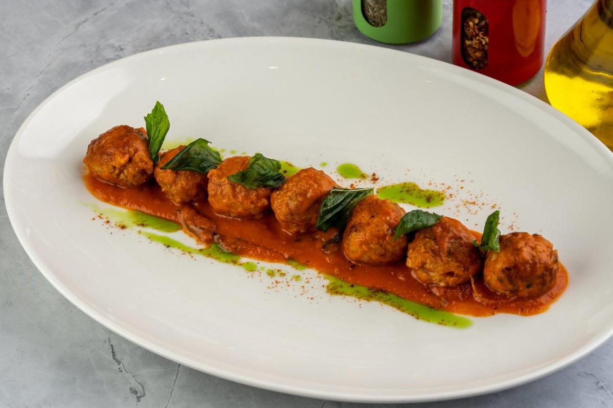 a plate of food with meatballs on a sauce at Holiday Inn New Delhi Aerocity by IHG in New Delhi